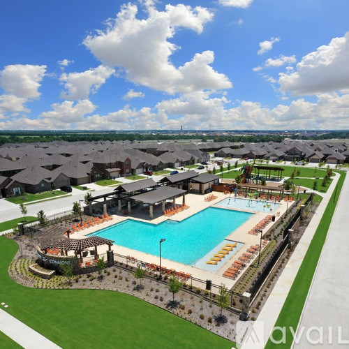 A large swimming pool surrounded by a grassy area and a few buildings in the distance.