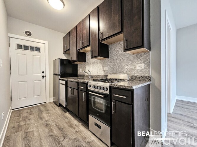A kitchen with black cabinets and a white door.