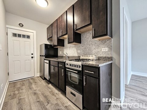A kitchen with black cabinets and a white door.