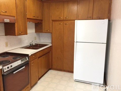 A kitchen with brown cabinets and a white refrigerator.