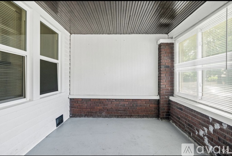 A white door is in the middle of a room with a wooden ceiling and brick wall.