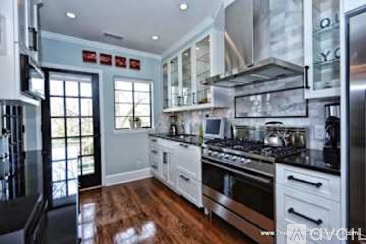 A modern kitchen with a black stove top oven and white cabinets.