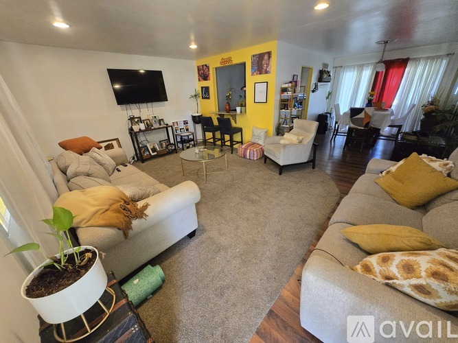 A living room with a grey sofa and a yellow accent wall.