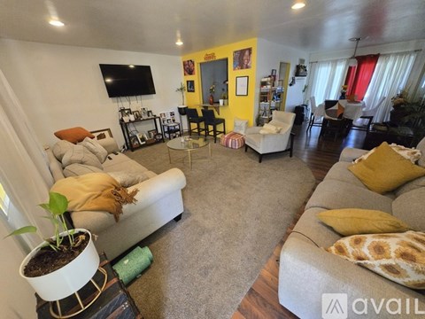 A living room with a grey sofa and a yellow accent wall.