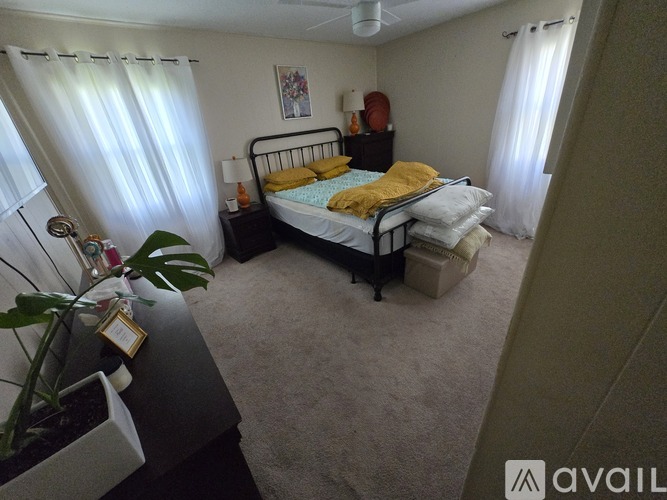 A bedroom with a bed, nightstand, and window with curtains.