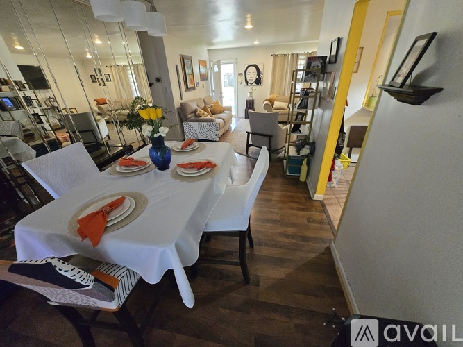A dining room with a table set for two and a vase of flowers.