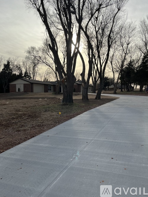 A sidewalk in a residential area with houses and trees.