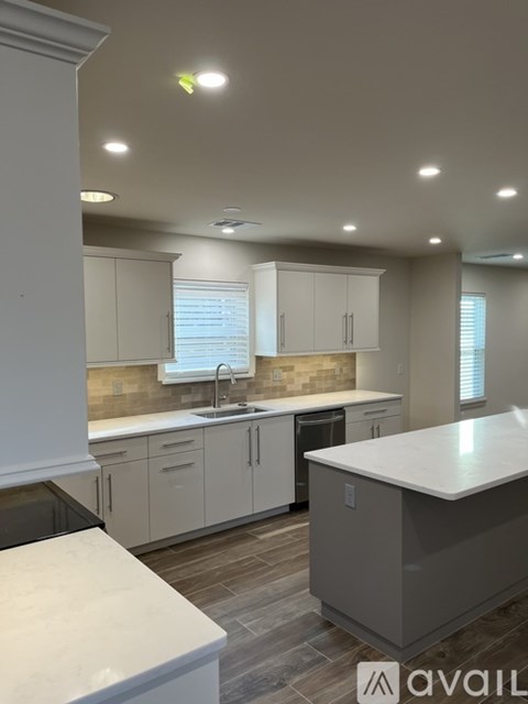 A kitchen with white cabinets and a marble countertop.