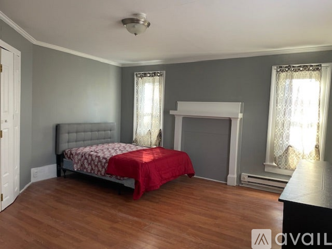 A bedroom with a bed, fireplace, and two windows.