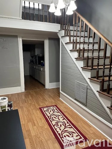 A staircase with a wooden handrail and a rug on the floor.