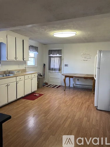 A kitchen with white cabinets and a wooden floor.