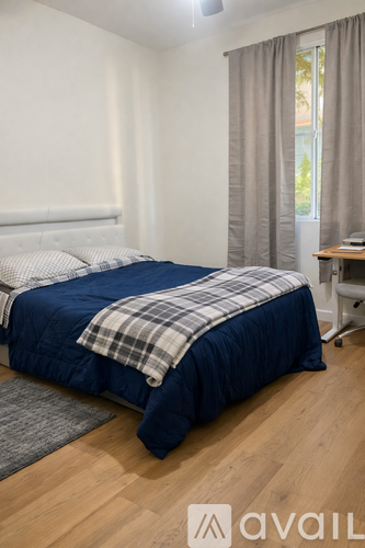 A bedroom with a large bed, a ceiling fan, and a chair.