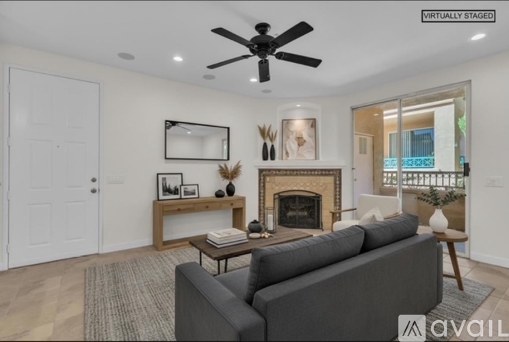 A living room with a grey couch, a fireplace, and a ceiling fan.