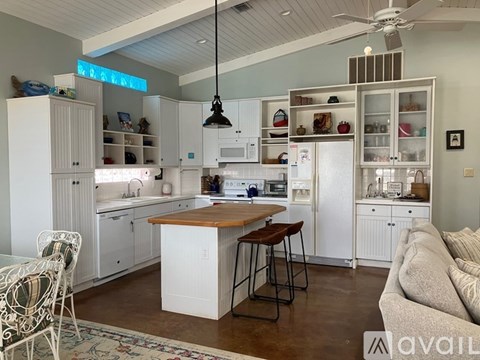 A kitchen with white cabinets and a wooden island.