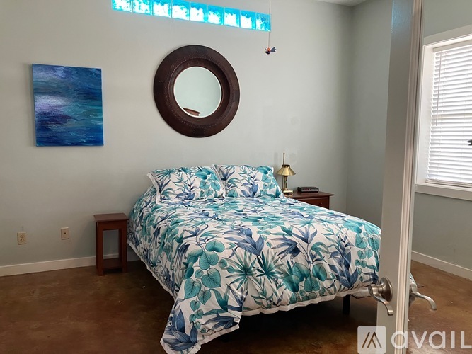 A bedroom with a bed, a mirror, and a painting on the wall.