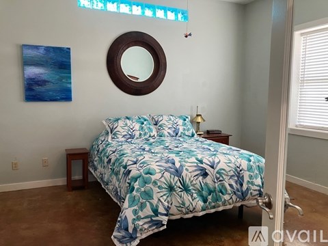 A bedroom with a bed, a mirror, and a painting on the wall.