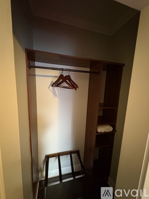 A wooden closet with a hanger and a shelf.