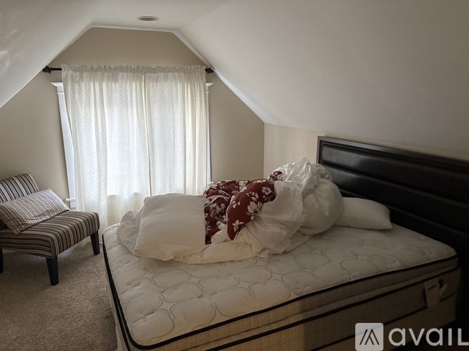 A bedroom with a large bed and a striped chair.