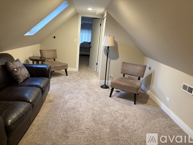 A living room with a black leather couch and a brown chair.