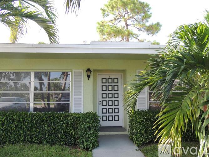 A white house with a green lawn and a white fence.