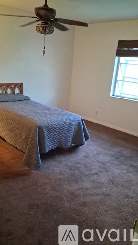 A bedroom with a bed covered in a blue blanket and a ceiling fan.
