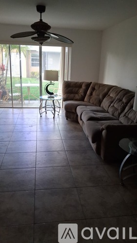 A living room with a brown couch and a ceiling fan.