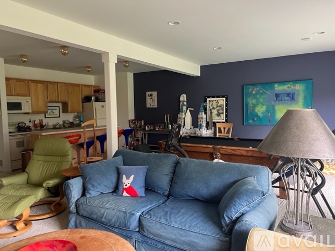 A blue couch with a red pillow is in the middle of a living room.