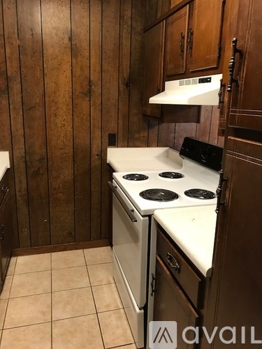 A small kitchen with a white stove and wooden cabinets.