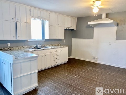 A kitchen with white cabinets and a marble countertop.