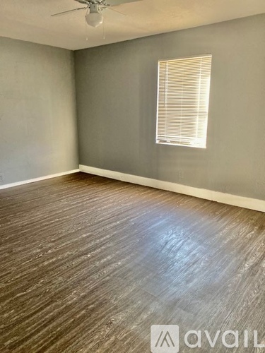 A room with wooden flooring and a window with blinds.