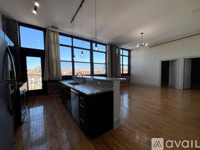 A spacious kitchen with dark wood floors and a large island in the middle.