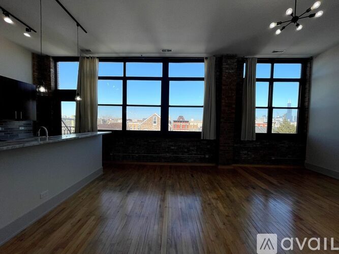 A spacious room with wooden floors and large windows overlooking a cityscape.