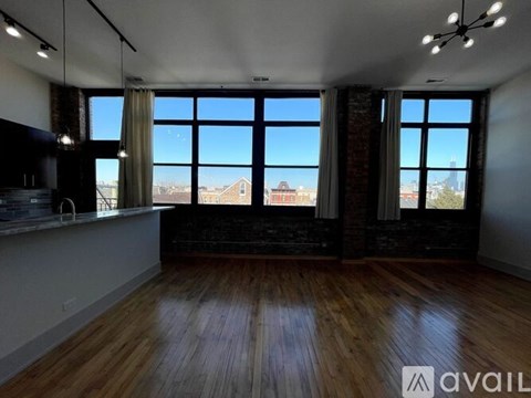 A spacious room with wooden floors and large windows overlooking a cityscape.