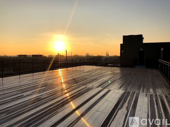 The sun is setting behind a building with a wooden roof.