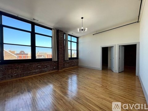 A spacious room with wooden floors and large windows.