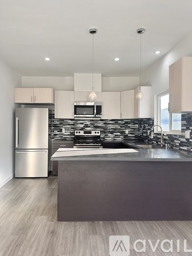 A modern kitchen with a stainless steel refrigerator and a central island.