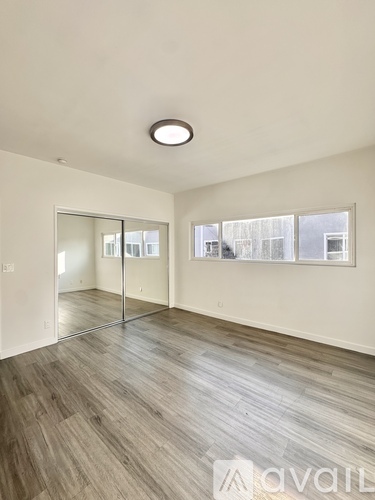 A spacious room with wooden flooring and a large mirror on the wall.
