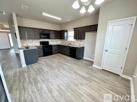A spacious kitchen with dark brown cabinets and a black stove top oven.