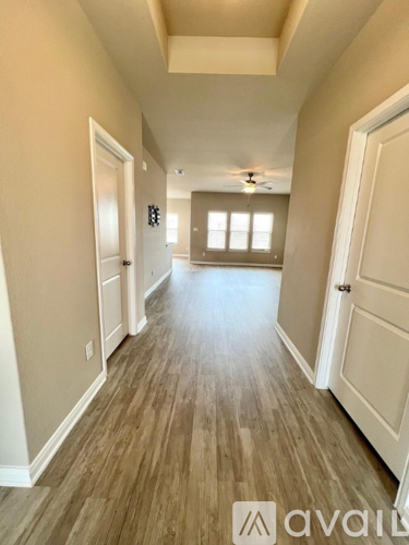 A hallway with wood flooring and white walls.