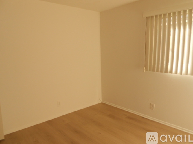 A room with wooden flooring and a window with blinds.