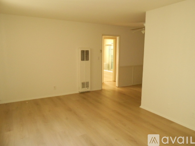 A room with wooden flooring and a doorway leading to another room.