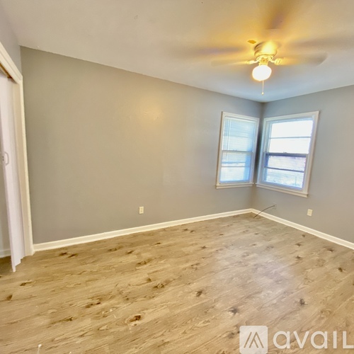 A room with a ceiling fan and two windows.