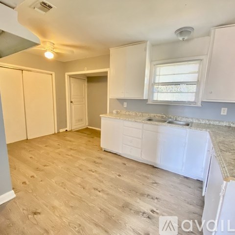 A kitchen with white cabinets and a window.