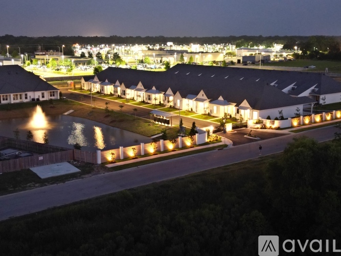 A nighttime view of a resort with illuminated buildings and a lit pool.