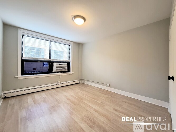 A room with a window and a fan on the window sill.