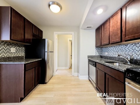 A kitchen with dark wood cabinets and a black fridge.