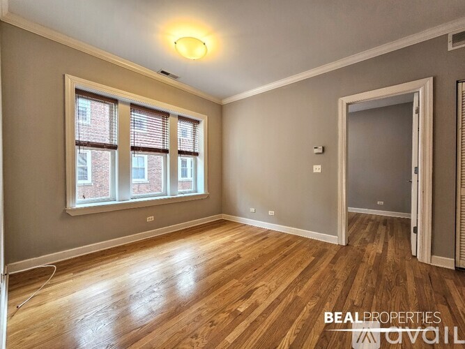 A room with wooden flooring and a window with blinds.