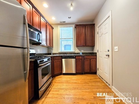 A kitchen with wooden cabinets and a stainless steel refrigerator.