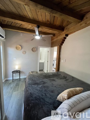 A bedroom with a bed, a ceiling fan, and a small table.