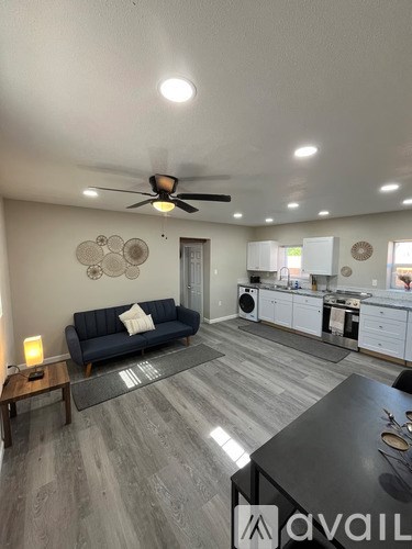 A living room with a blue couch and a kitchen in the background.